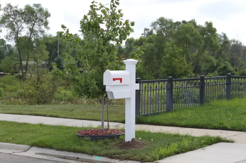 White mailbox beside metal fence