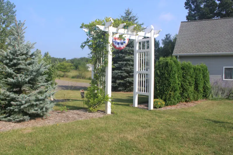 White arbor in landscaped garden